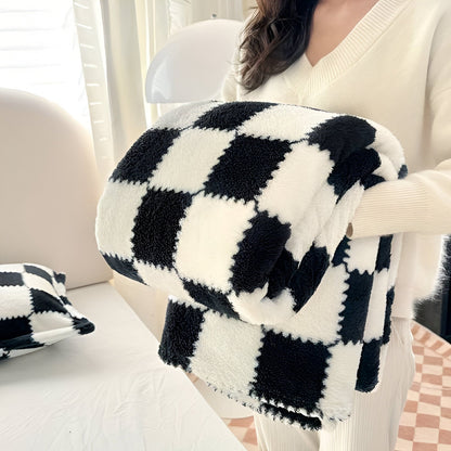Teddy fleece deken met dambordpatroon, opgevouwen in de armen - zwart